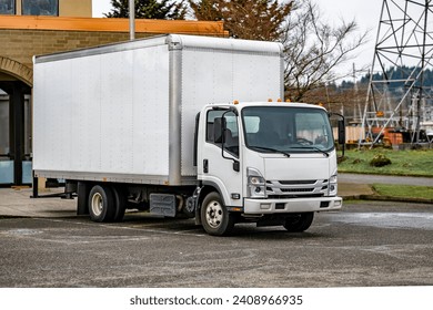 Middle duty Industrial standard white cab over rig semi truck with box trailer for local deliveries and small business needs unloading goods standing on the parking lot - Powered by Shutterstock