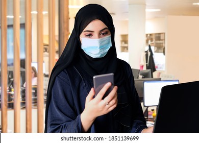 Middle East Going Back To Work Due To COVID19 Pandemic Wearing Face Mask And Arab Abaya Hijab While Using Smart Phone.