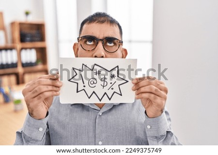 Middle east man with beard holding banner with swear words angry and mad screaming frustrated and furious, shouting with anger looking up. 