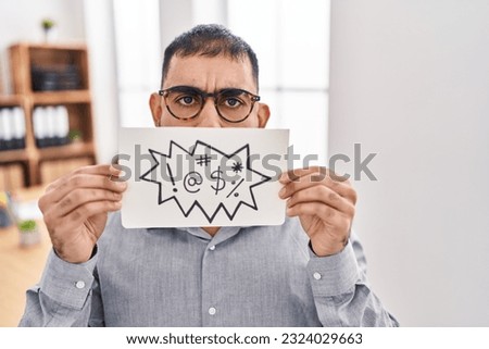 Middle east man with beard holding banner with swear words angry and mad screaming frustrated and furious, shouting with anger. rage and aggressive concept. 