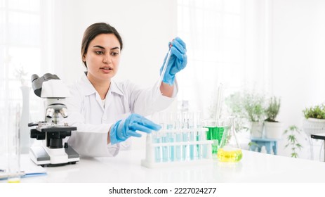 Middle East woman scientist researcher use a lab dropper to drip a substance into a test tube for analysis of liquids in the lab. Scientist working with a dropper and a test tube. - Shutterstock ID 2227024277