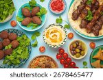 Middle eastern or Arab dishes and assorted meze on light beige background. Meat kebab, falafel, hummus, sambusak, rice, kibbeh, pita. Halal food. Lebanese cuisine