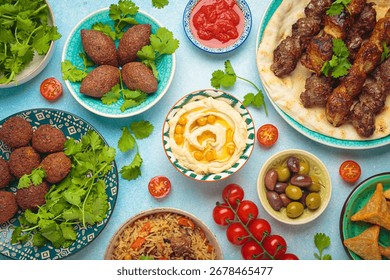 Middle eastern or Arab dishes and assorted meze on light beige background. Meat kebab, falafel, hummus, sambusak, rice, kibbeh, pita. Halal food. Lebanese cuisine
