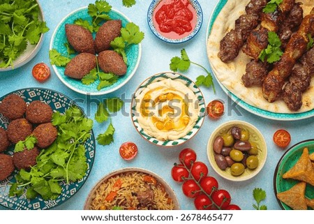 Middle eastern or Arab dishes and assorted meze on light beige background. Meat kebab, falafel, hummus, sambusak, rice, kibbeh, pita. Halal food. Lebanese cuisine