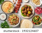 Middle eastern or arabic cuisines, falafel, hummus, tabouleh, pita and vegetables on a concrete background, view from above