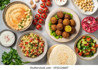 Middle eastern or arabic cuisines, falafel, hummus, tabouleh, pita and vegetables on a concrete background, view from above
