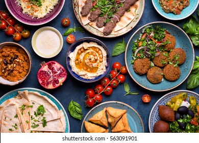 Middle Eastern Or Arabic Dishes And Assorted Meze, Concrete Rustic Background. Meat Kebab, Falafel, Baba Ghanoush, Muhammara, Hummus, Sambusak, Rice, Tahini, Kibbeh, Pita. Halal Food. Lebanese Cuisine