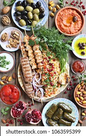 Middle Eastern, Arabic Or Mediterranean Dinner Table With Grilled Lamb Kebab, Chicken Skewers  With Roasted Vegetables And Appetizers Variety Serving On Party Outdoor Table. Overhead View.