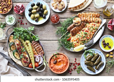 Middle Eastern, Arabic Or Mediterranean Dinner Table With Grilled Lamb Kebab, Chicken Skewers  With Roasted Vegetables And Appetizers Variety Serving On Party Outdoor Table. Overhead View.