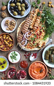 Middle Eastern, Arabic Or Mediterranean Dinner Table With Grilled Lamb Kebab, Chicken Skewers  With Roasted Vegetables And Appetizers Variety Serving On Rustic Outdoor Table. Overhead View.