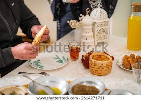 Middle Eastern dining scene with bread, tea, falafel, hummus, olive oil, and juice, capturing traditional Arabic cuisine and warm cultural hospitality.