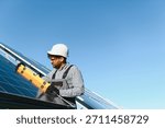 Middle eastern engineer uses a level tool while installing a solar panel on a clear day, promoting renewable energy and sustainable practices