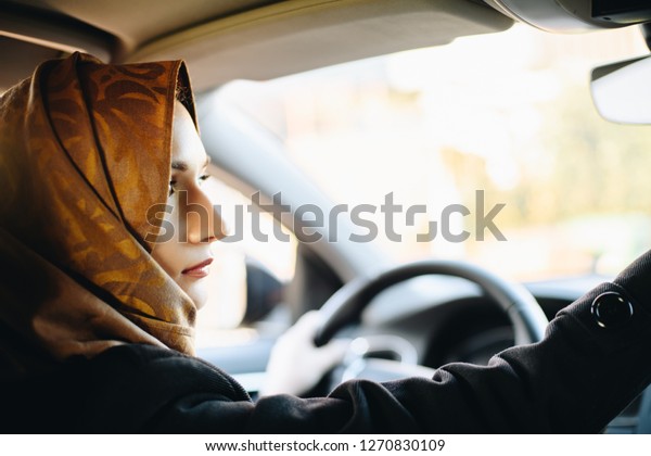 Middle eastern ethnicity woman in car as\
driver. Arabic woman in hijab driving a\
car
