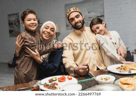 Middle eastern family hugging kids during ramadan dinner at home