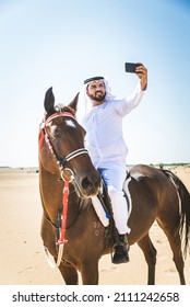 Middle Eastern Handsome Man With Typical Emirates Dress Riding A Arabic Horse In The Dubai Desert