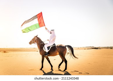 Middle Eastern Handsome Man With Typical Emirates Dress Riding A Arabic Horse In The Dubai Desert