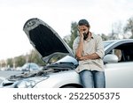 middle eastern Man experiencing car trouble in a parking lot, expressing frustration while standing beside his broken vehicle