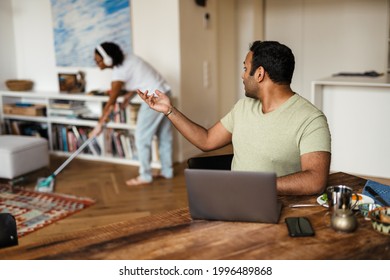 Middle eastern man working with laptop and talking with his girlfriend at home