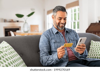 Middle eastern mature man using credit card to make online payment on smartphone. Mixed race man using cellphone for shopping online. Guy using smart phone to check credit card transactions from app.