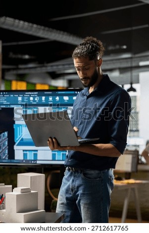 Middle eastern real estate developer evaluates construction site digital blueprints on laptop, working on urban housing project for infrastructure growth. Structural design for smart city.