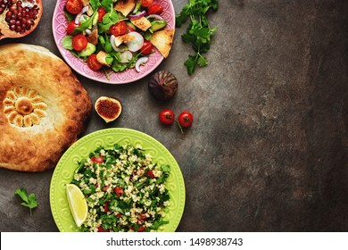 Middle Eastern Salads Tabbouleh And Fattoush, Pitta Bread, Pomegranate, Figs On A Dark Rustic Background. Arabic Dishes, Top View