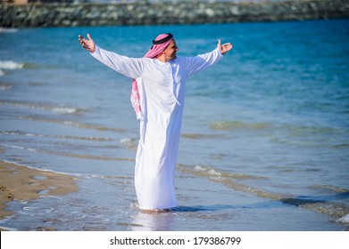 Middle Eastern way dressed Arab man poses in front of sea coast. 