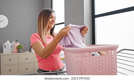 Middle eastern woman smiling looking clothes of basket at laundry room - Shutterstock ID 2311797143