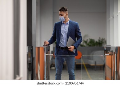 Middle Eastern Young Man In Protective Face Mask Holding Electronic Entrance Gate Card And Laptop, Worker Passing Access Building Security System At Office, Panorama With Copy Space