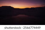 In the middle of Icelandic geysers, strong evacuation of toxic or volcanic clouds, between rocks, at dusk, sunset, natural phenomenon, dark orange and purple sky, people and tourists walking through 