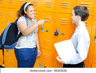 Middle School Boy And Girl Laughing And Joking Together By Their Lockers.