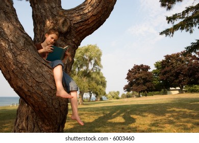 A Middle School Girl Reading A Book While Sitting Up In A Tree.