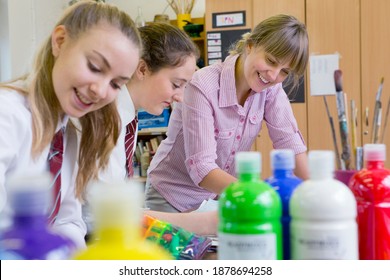 Middle School Students Painting In An Art Class With An Art Teacher Guiding Them.