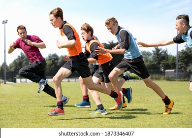 Middle schoolboys and teacher running while playing rugby on the field in physical education class - Powered by Shutterstock