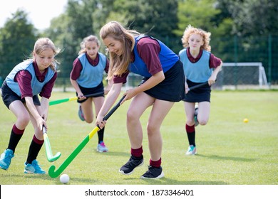 Middle schoolgirls playing hockey on the field in physical education class