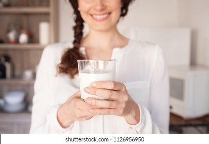 Middle Section Of Beautiful Middle Age Woman In Home Kitchen With Hands Holding Glass Of Milk Wearing White, Faceless Smiling Indoors. Healthy Female Drinking Calcium Fresh Organic Milk, Lifestyle.