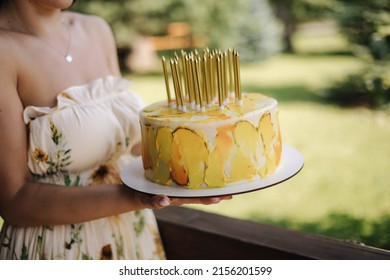 Middle selection of female hold her yeallow bithday cake outdoor. Happy bithday to me. Concept of summer patry on terrace