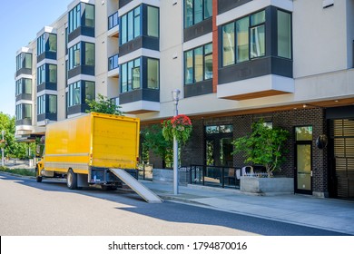 Middle Size Compact Yellow Rig Semi Truck Delivering Cargo In Box Truck Standing On The Street Parking Spot With Multilevel Buildings Waiting For Unloading Delivered Stuff