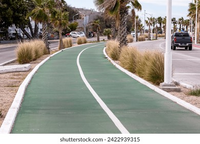 Middle strip or central reservation of avenue with bicycle lane, coastal area of city, cars circulating, buildings and palm trees in background, Cloudy day in La Paz, Baja California Sur Mexico - Powered by Shutterstock