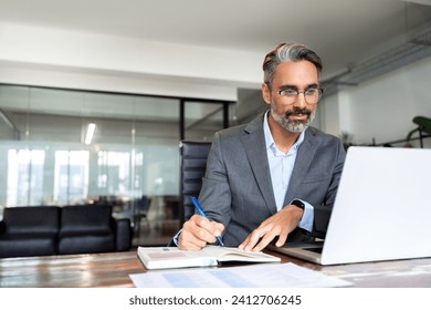 Middle-age Hispanic man using laptop computer for business studying, watch online virtual webinar training meeting, video call. Focused mature Indian or Latin businessman work in office, copy space. - Powered by Shutterstock