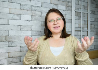 Middle-aged Adult Woman With Glasses Communicates From Home Via Video Link, Gestures With Her Hands, Concept Of Remote Education, Video Conferencing, Lockdown Covid-19