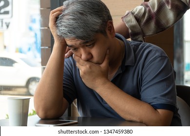 Middle-aged Asian Man 40 Years Old, Stressed And Tired, Are Sitting In Fast Food Restaurant And Have Friends Standing Behind To Encourage. Concept Of Helping And Encouraging