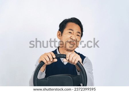 A middle-aged Asian man feels irritated while holding the steering wheel and driving a car.