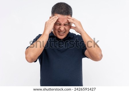 A middle-aged asian man with pained expression holding his head, indicating an excruciating migraine or headache. Isolated on white.