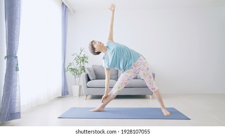 Middle-aged Asian woman doing yoga in room.