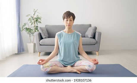 Middle-aged Asian woman doing yoga in room. Mindfulness. - Powered by Shutterstock