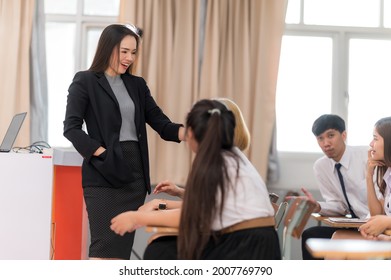 A Middle-aged Asian Woman Teacher Helping A Student During On A Class In The Classroom University 