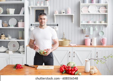 Middle-aged athlete, holding a bowl of a plate with a prepared salad of cucumber and tomato. - Powered by Shutterstock