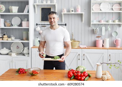 Middle-aged athlete, holding a bowl of a plate with a prepared salad of cucumber and tomato. - Powered by Shutterstock