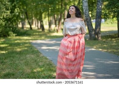 Middle-aged attractive woman with dark hair, enjoying nature in the forest. Walking among the trees in the sunlight. self-sufficient confident woman