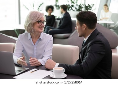 Middle-aged broker insurer manager consulting man client explains insurance services deal benefits make business offer to customer during formal meeting in office. Coach teach intern, teamwork concept